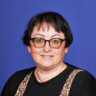 Woman with glasses smiles wearing black top and animal print FairmeadSchool