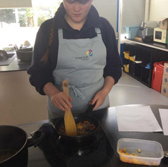 Teenager cooking with a wooden spoon, FairmeadSchool. Cooking class at school.
