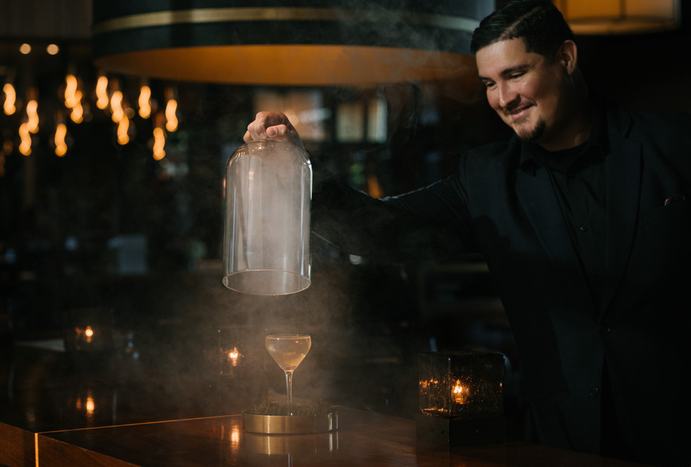 Male bartender unveiling a cocktail with dramatic smoke effect at upscale bar in Los Angeles captured by the best luxury food and beverage photographer in LA and Santa Barbara, Montecito - Anna Kreative Studio