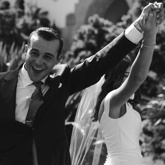 Bride and groom raise their arms in celebration at the Santa Barbara Courthouse, captured by Anna Kreative Studio's non-intrusive wedding photographer