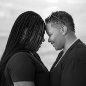 Close-up, heartfelt portrait of a same-sex, gay couple of color sharing an intimate and loving gaze in Santa Barbara, California. The image beautifully captures the depth of their connection and the tenderness in their expressions, framed by the serene, sunlit landscape of Santa Barbara, celebrating love in all its forms.