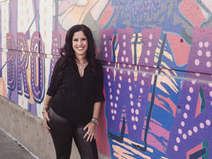 Alicia smiling leaning against a graffiti wall