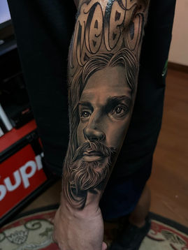 Tatuagem realista de Jesus Cristo em preto e cinza, feita por Bruno Felipini, tatuador em Curitiba.