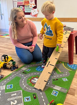 This image is a lady and a boy playing with cars on a ramp. They are using ready steady go as a strategy to communicate.