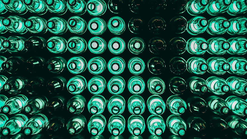 Rows of teal-green glass bottles viewed from below in a dark rack, creating an abstract glowing pattern.