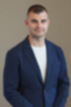 Alan Reed wearing a blue blazer and white t-shirt, studio portrait.