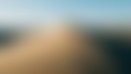 Lone hiker stands atop a sand dune, footprints trailing behind in a vast desert under a clear blue sky.