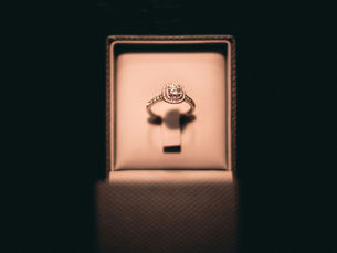 Diamond engagement ring in a velvet jewelry box, lit warmly against a dark background.