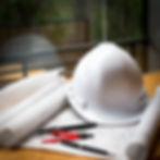 Hardhat, pens, and the floorplan of a house