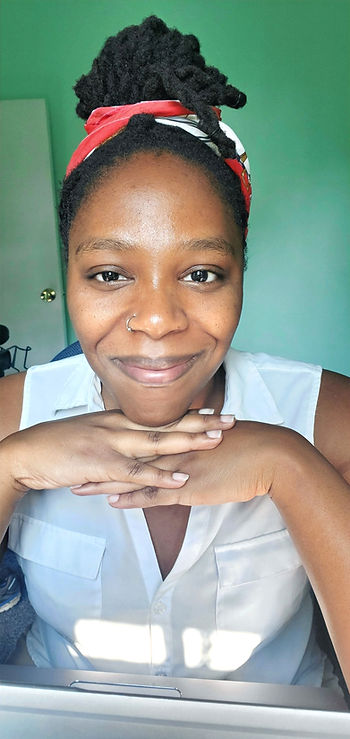 The author sitting at her desk smiling with her chin resting on her hands.