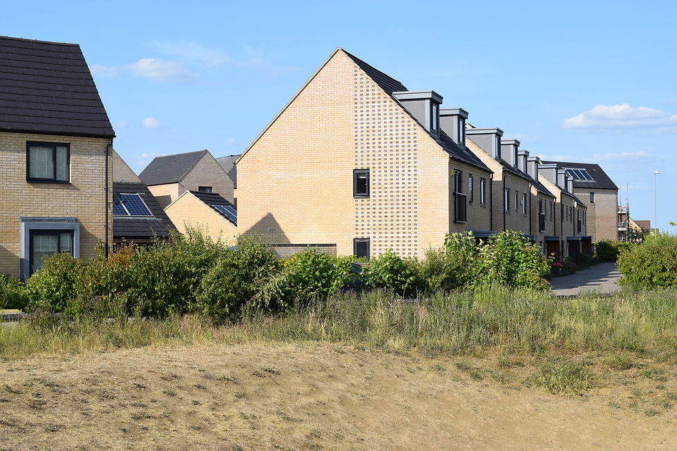 A row of sleek, modern houses with intricate brickwork, pitched roofs fitted with dormer w