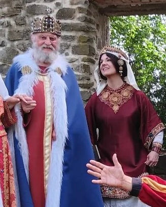 Roswitha (Hrotsvit) von Gandersheim, Theater und historische Walk Act, erste bekannte deutsche Dichterin aus dem 10. Jhdt., Theater, Gedicht, Vortrag, Lesung und Walk Act in früh mittelalterlichem Gewand, byzantinische Mode in roter Seide mit Stickereien, aufwendigem Hals- und Schapel Kopfschmuck byzantinische Mode in rot und gold, verbeugt sich vor Darsteller Otto I dem Großen mit Replik Krone. bei Veranstaltungsreihe "Des Kaisers letzte Reise"