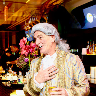 Ein charmanter Conférencier und Moderator in barockem Kostüm mit Perücke unterhält die Gäste bei einem festlichen Dinner. Ideal für historische Shows, Walk Acts und märchenhafte Dinner-Events.