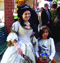 Sophie Charlotte von Hannover, Königin in Preußen, Theater, Tanz, historische Walk Act, historische Frau in silbernem Barock Kostüm mit goldener Spitze und Barock Frisur mit Kopfschmuck, lächelt und posiert mit jungem Mädchen Theaterstück und Walk Act zu Sophie Charlottes Todesjahr beim Sommerzauber Los Angeles Platz Berlin