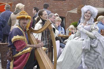 Dame in weißem Rokoko Barock Gewand mit weißer Perücke singt, daneben ein Harfenspieler