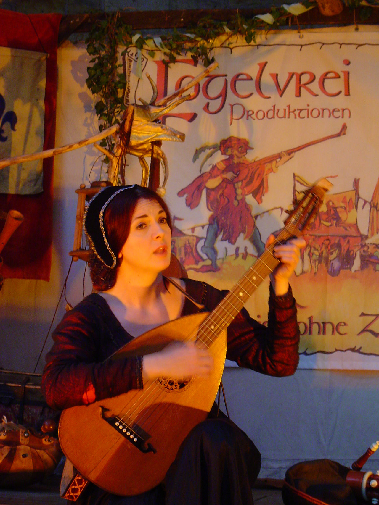 Lidia Buonfino in einer szenischen Rezitation mit musikalischer Begleitung, inspiriert von der Renaissance. In authentischem Gewand und mit Laute vor historischer Kulisse präsentiert sie poetische Lyrik und erzählerische Kunst. Die Darbietung verbindet Musik und Poesie zu einer stimmungsvollen Inszenierung der Vergangenheit.