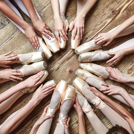 Legs, with ballet slippers adorning feet, arranged in a circle on the floor.