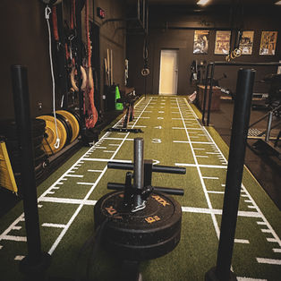 Trainingsschlitten mit Gewichtsscheiben auf der grünen Athletikbahn im DOJO Essen