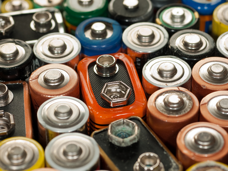 Close-up image of various used household batteries, including AA, AAA, C, D, and 9-volt types, highlighting the importance of proper battery disposal and recycling.