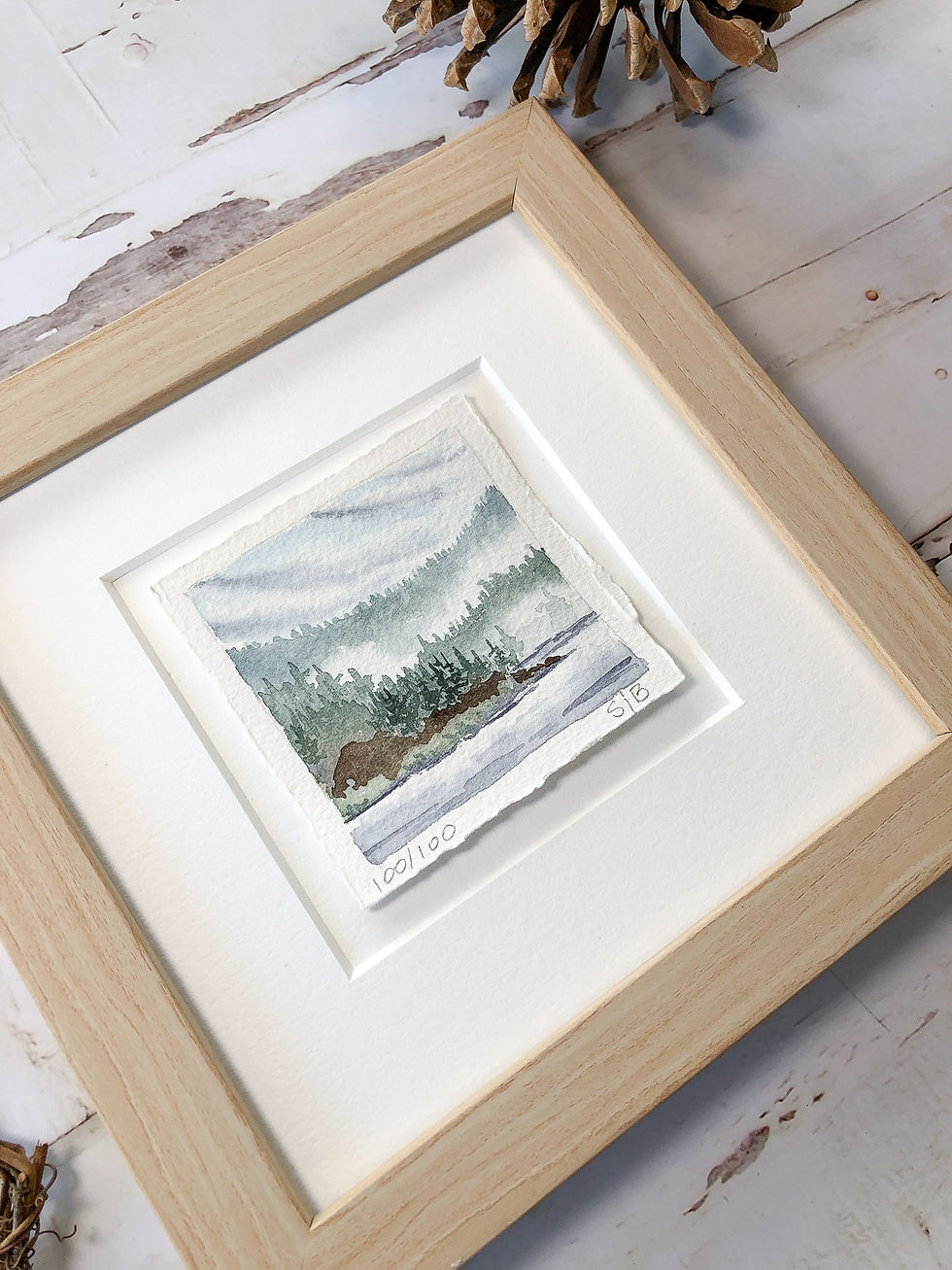 Thumbnail: miniature watercolor landscape of clouds lifting over a lake after a summer rain shower, calming blues and greens, mat detail