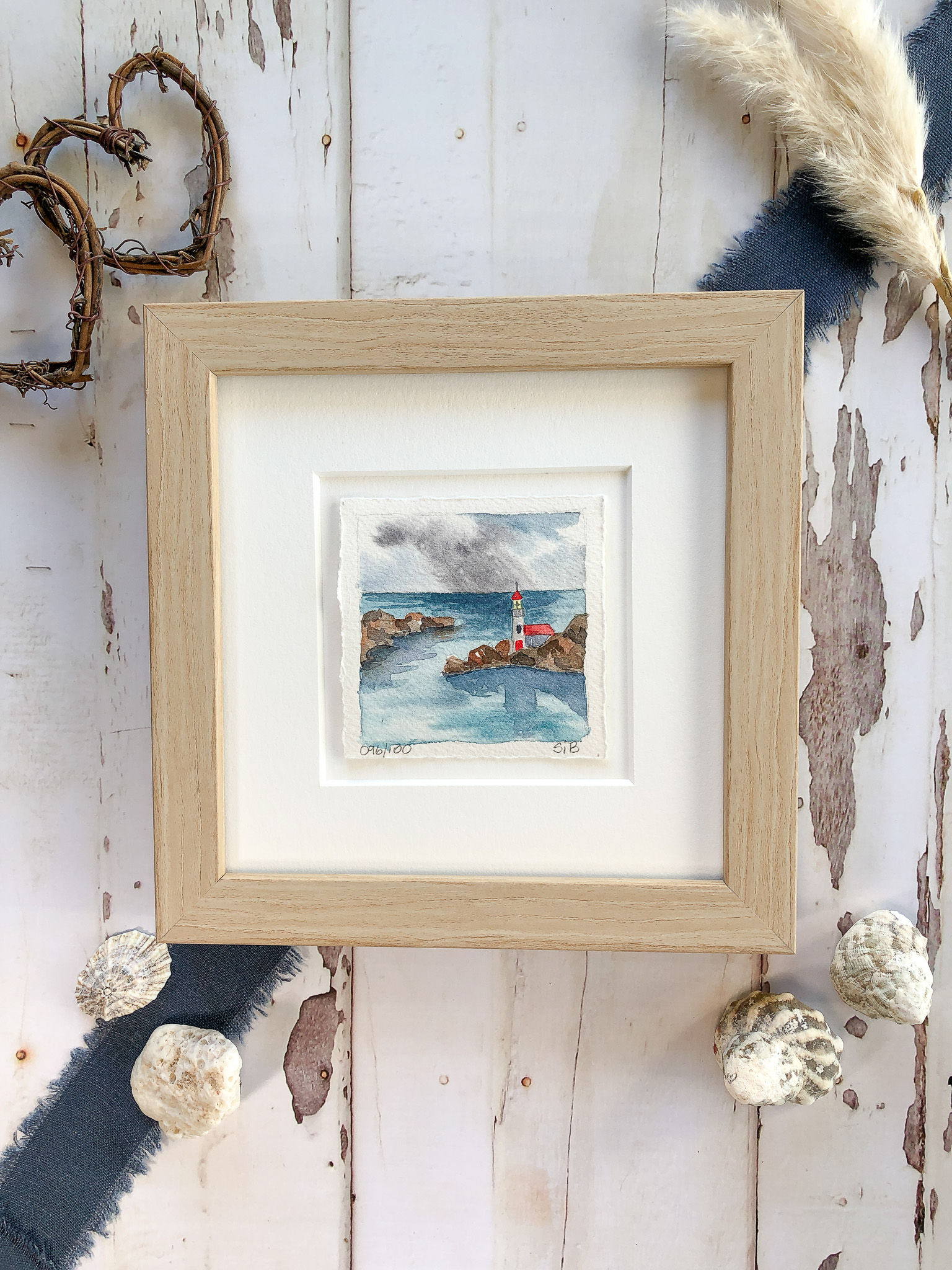 miniature watercolor seascape of ocean and lighthouse perched upon a rocky point, framed