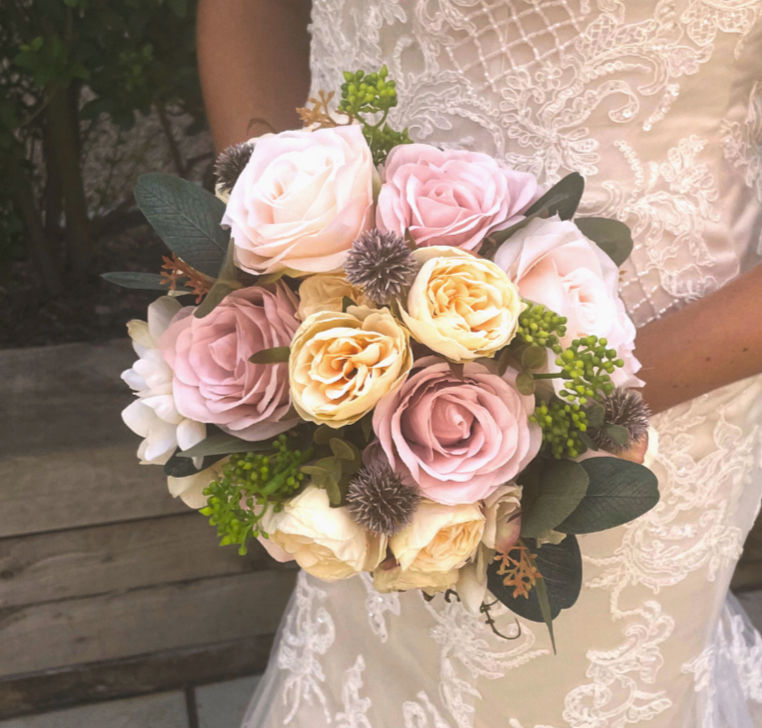Light Pink, Cream Rose and Purple Globe Thistle Bridal Bouquet Collection being held by a bride