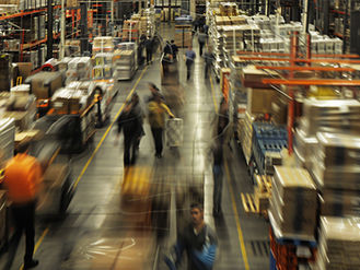 Busy warehouse with temporary workers walking down the aisle, representing efficient staffing solutions and flexible labor support provided by a staffing agency.