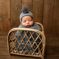Newborn baby Eliab posed in a wicker crib prop wearing a knit hat during Aurora newborn photography session