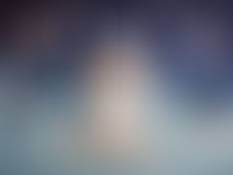 Sleeping newborn boy in cream knit outfit and cap posed safely on a wooden swing against a blue starry sky backdrop with felt elephant balloons in an Aurora Colorado newborn photography studio.