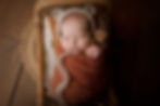 Aurora Colorado | Newborn Photographer | Tiny Details Photography | New baby girl wrapped in criss cross green wrap on matching green bunny fur and fabric background wrapped with toes out and wearing a crocheted green bonnet while smiling