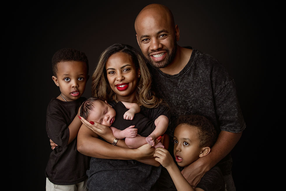 Family of five posing together with newborn baby Eliab in a dark studio portrait during an Aurora newborn photography session