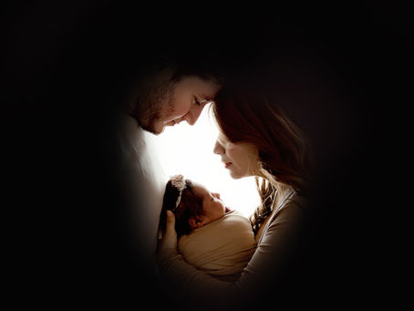Emotional newborn portrait with first-time parents in a cozy Aurora, Colorado studio, gently cradling their swaddled baby girl during a Tiny Details Photography session.