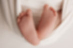 Close-up of a newborn’s tiny feet resting softly in a white wrap during a studio newborn photography session in Aurora, Colorado.
