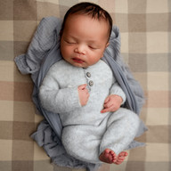 Newborn baby Eliab wearing a soft blue outfit posed on a neutral plaid background during Aurora newborn photography session