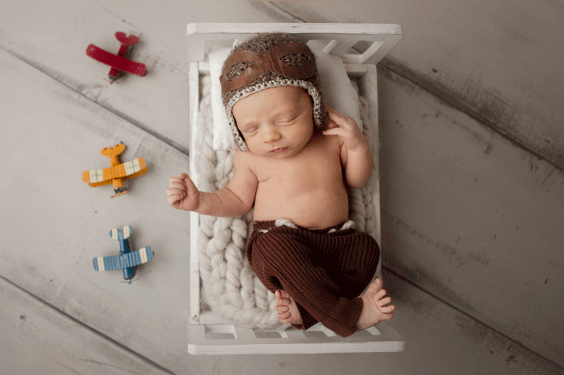 Aurora Colorado | Newborn Photographer | Tiny Details Photography | Newborn baby girl with name spelled out in learning wood blocks to say lottie while baby is holding an apple and wearing glasses