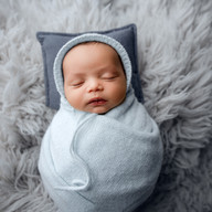 Newborn baby Eliab posed in a wicker crib prop wearing a knit hat during Aurora newborn photography session