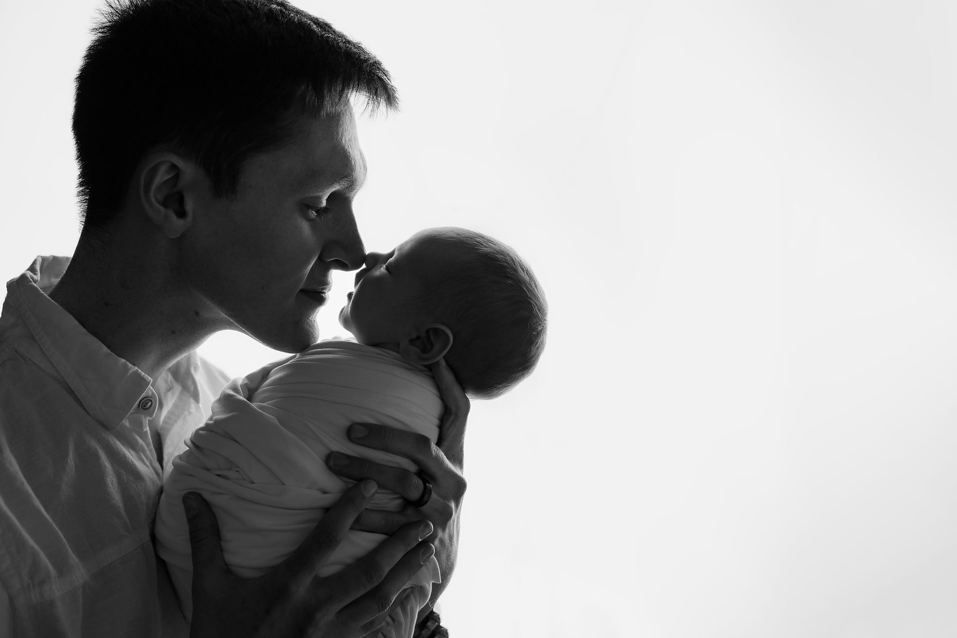 backlit image of dad holding newborn baby