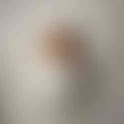 Newborn baby girl wrapped in white, wearing a tiny nurse hat with a red cross, posed with a stethoscope on a light wooden backdrop.