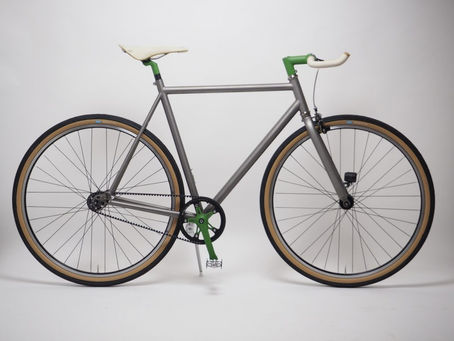 Nua Floc de Neu titanium fixie, featuring a Gates belt drive, green components and tan-wall tyres.