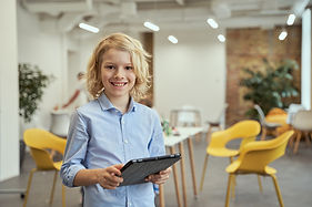 portrait-adorable-little-boy-smiling-camera-using-tablet-pc-while-posing-classroom.jpg