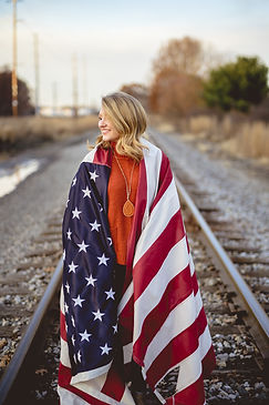vertical-shot-female-with-american-flag-her-shoulders-standing-railway (1).jpg
