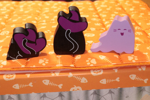 The reverse side of meeples from left to right on top of the game quilt from BOOoop. the witchy purple Kitten, witchy purple Cat and purple Ghost Cat