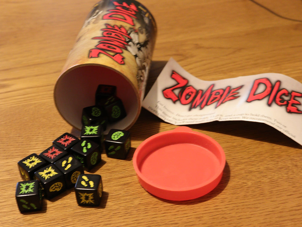 The game Zombie dice spilling out of the game box onto a wooden table showing the dice and the rules pamphlet