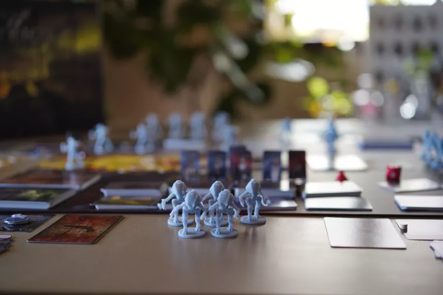 Some miniatures from the game Patriot in front of a blurred background of game components