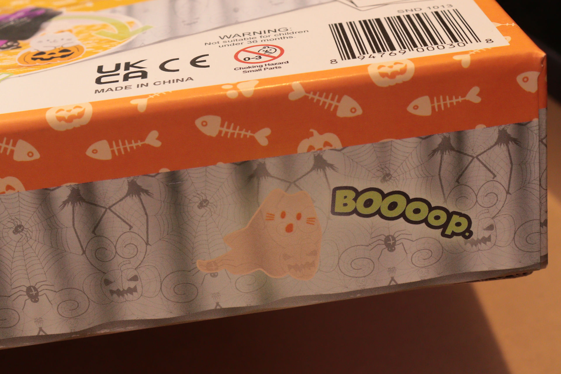 A closeup of one of the sides of the box of the BOOoop. game box. It features the transparent orange cat and the word BOOoop.