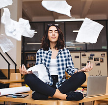 jeune-femme-brune-assez-joyeuse-meditant-table-entourent-trucs-travail-papiers-volants-bon