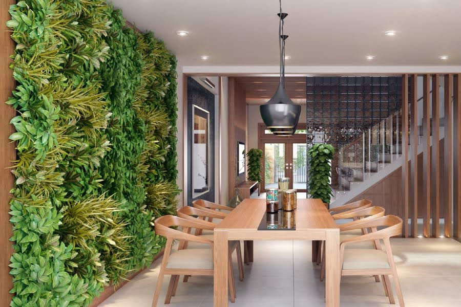 Modern dining room with a wooden table, chairs, and a pendant light. Green vertical garden on the wall, staircase in the background.