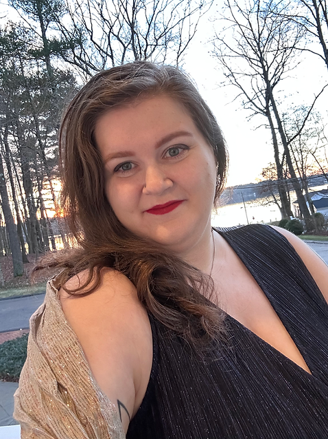 Photo of a femme woman with wavy hair and a sparkly blue outfit with a winter sunset in the background