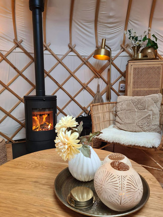 Brandende houtkachel en zithoek met sfeerverlichting – voor een warm en intiem samenzijn in Yurt Sirius.