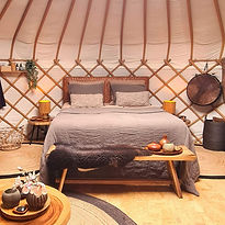Aards interieur van yurt Venus met bed in bruintinten en een warme sfeer voor twee.
